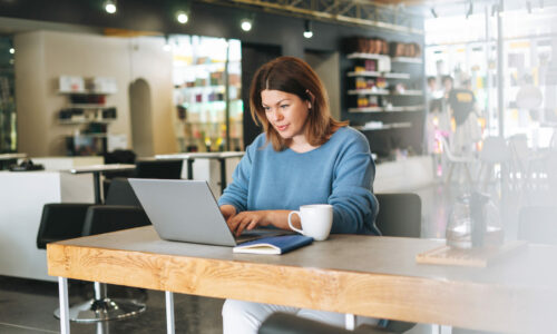 Beautiful stylish young woman plus size body positive using laptop at the beauty salon office, small business owner