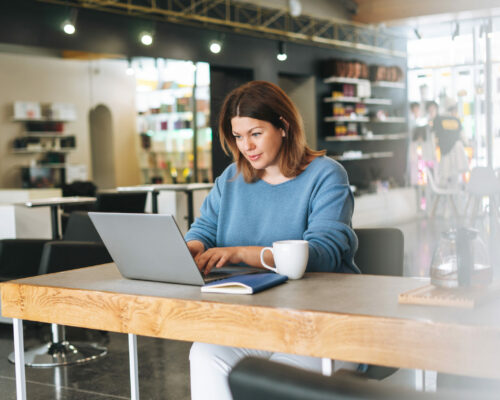 Beautiful stylish young woman plus size body positive using laptop at the beauty salon office, small business owner