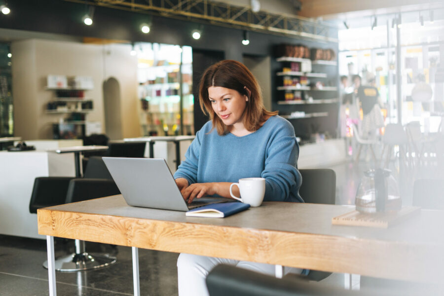 Beautiful stylish young woman plus size body positive using laptop at the beauty salon office, small business owner