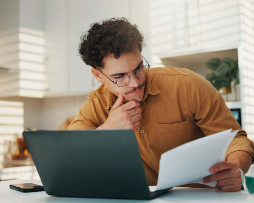 Man, documents and laptop for budget in home, review and stress for finance, investment and wealth planning. Person, computer and paperwork with taxes, bills and thinking with report at apartment.