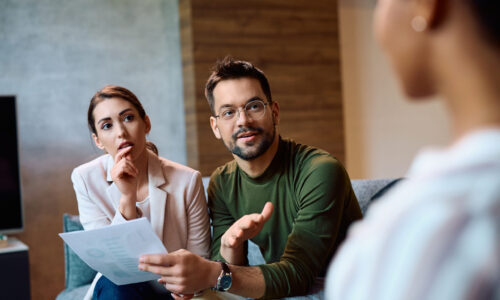 Young couple communicating with insurance agent while analyzing documents during meeting.